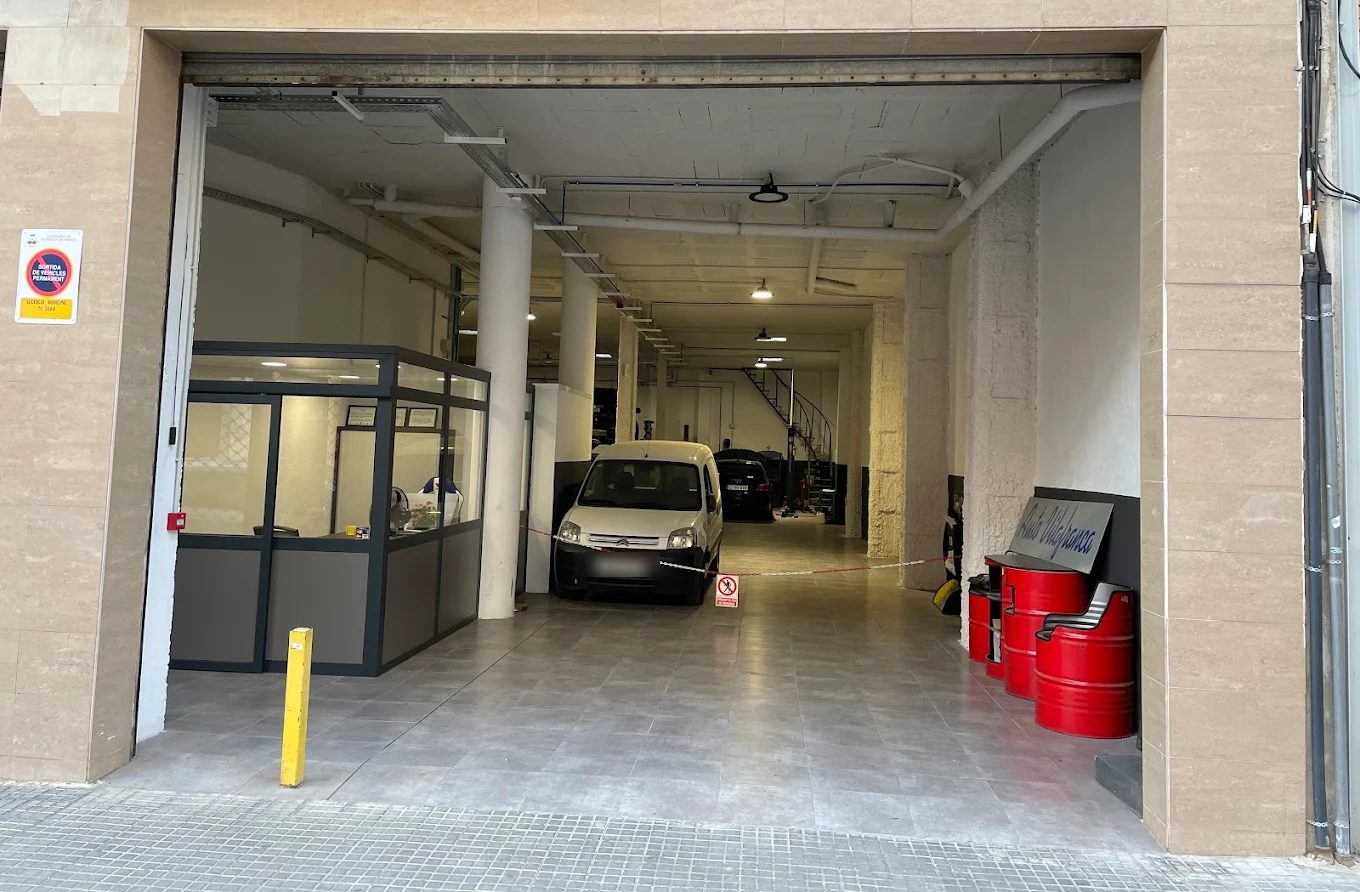 Entrada de Auto Vilafranca en el Carrer de Jaume Balmes, 23: portón abierto, oficina acristalada a la izquierda y el taller al fondo